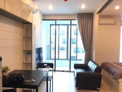 Modern studio apartment with open layout and balcony view, featuring sleek furniture and ample natural light.