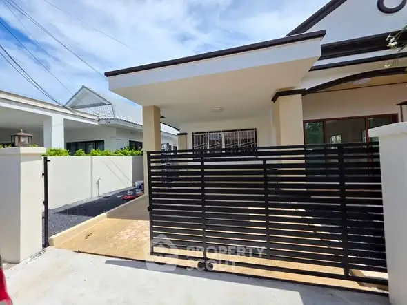 Charming single-story home with modern gate and driveway in a serene neighborhood.