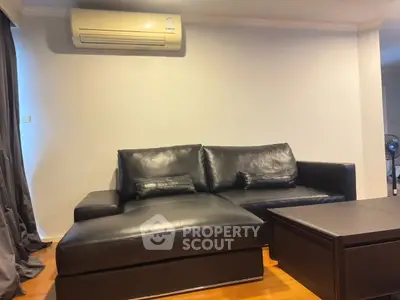 Modern living room with black leather sofa and air conditioning unit