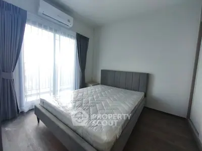 Spacious bedroom with large window and modern furnishings in a bright apartment.