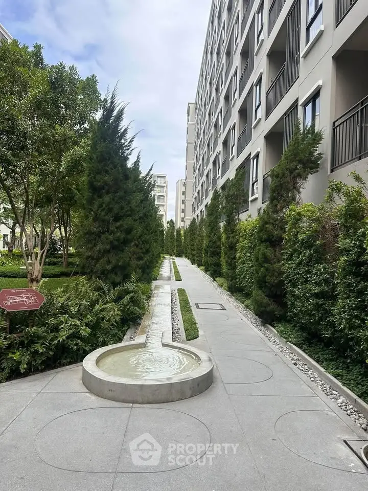 Modern apartment building exterior with lush greenery and water feature