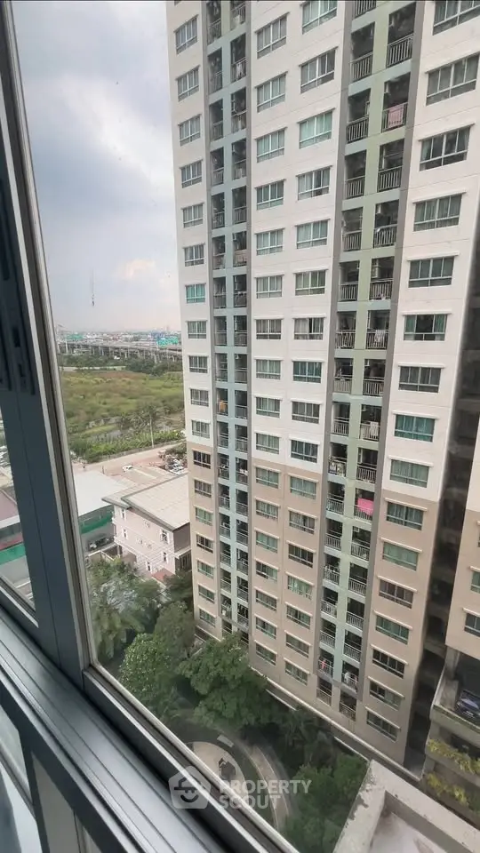 High-rise building view from window with lush greenery and urban landscape