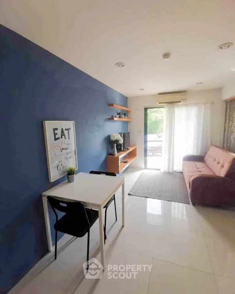 Modern living room with blue accent wall, cozy sofa, and dining area.