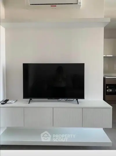 Modern living room with sleek TV unit and air conditioning, showcasing minimalist design and functionality.