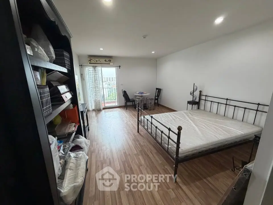 Spacious bedroom with balcony access and wooden flooring in modern apartment.