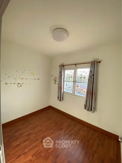 Bright empty room with wooden flooring and decorative wall art, perfect for customization.