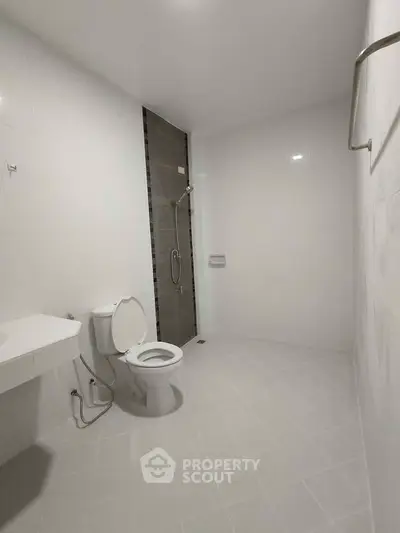 Spacious modern bathroom with white tiles and sleek fixtures.