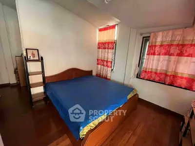 Cozy bedroom with wooden flooring and vibrant curtains