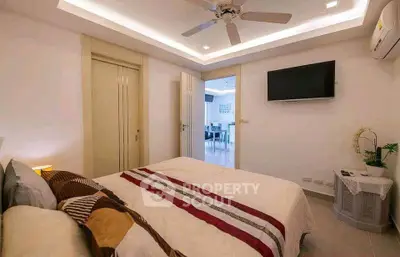Modern bedroom with ceiling fan and wall-mounted TV in stylish apartment