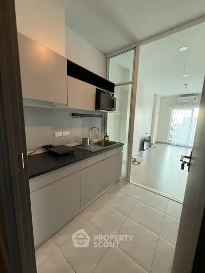Modern kitchen with sleek cabinetry and open layout leading to bright living area