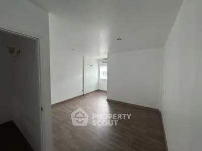 Spacious empty room with wooden flooring and white walls, ideal for customization.