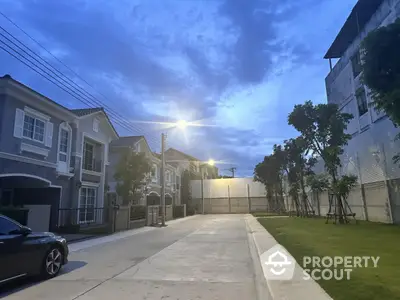 Charming suburban street with modern houses and lush greenery at dusk.