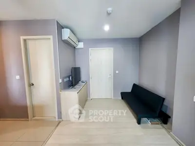 Modern living room with sleek design, featuring a minimalist black sofa and wall-mounted TV.