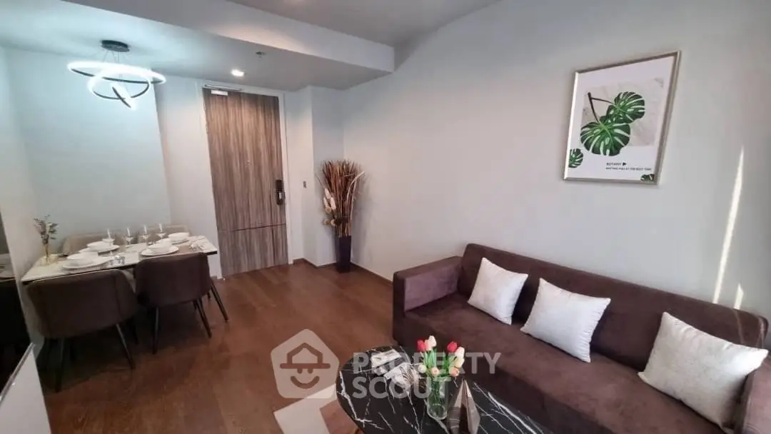 Modern living room with stylish decor and dining area, featuring elegant lighting and wooden flooring.