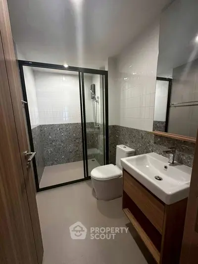 Modern bathroom with glass shower and sleek fixtures in contemporary apartment.