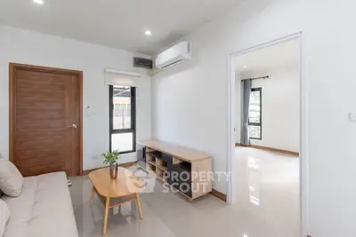 Modern living room with sleek furniture and natural light, featuring a cozy sofa and stylish wooden accents.