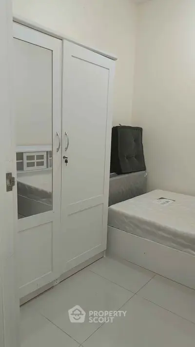 Cozy bedroom with white wardrobe and single bed, perfect for minimalist living.