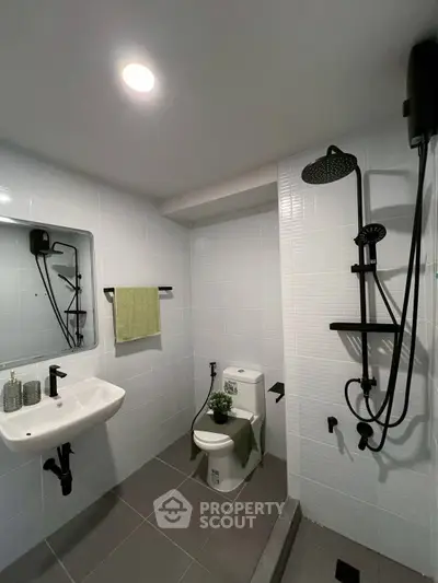 Modern bathroom with sleek black fixtures and white tiles, featuring a rain shower and stylish sink.