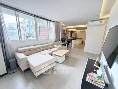 Spacious modern living room with open kitchen and large windows in urban apartment.