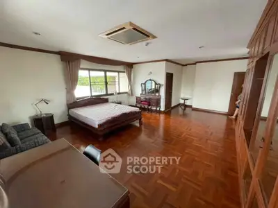 Spacious bedroom with wooden flooring and large windows in elegant home