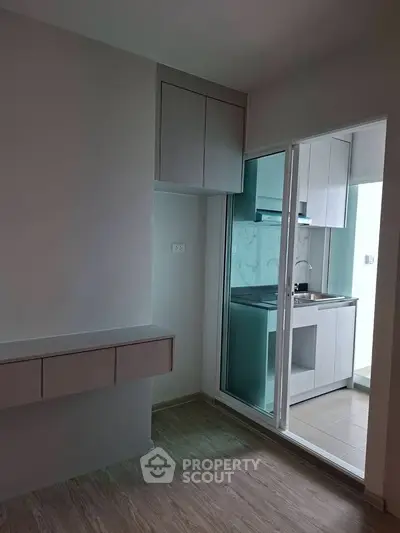 Modern kitchen with sleek cabinetry and glass sliding doors in a contemporary apartment.