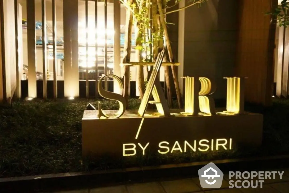 Elegant Sari by Sansiri entrance sign illuminated at night, showcasing luxury real estate branding.