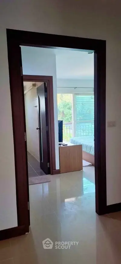 Bright interior view through doorway leading to a cozy living room with natural light.