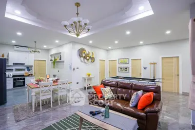 Spacious modern living room with open kitchen, elegant lighting, and stylish decor.