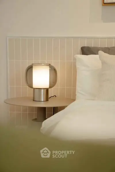 Modern bedroom with stylish lamp and cozy bedding, perfect for relaxation and comfort.