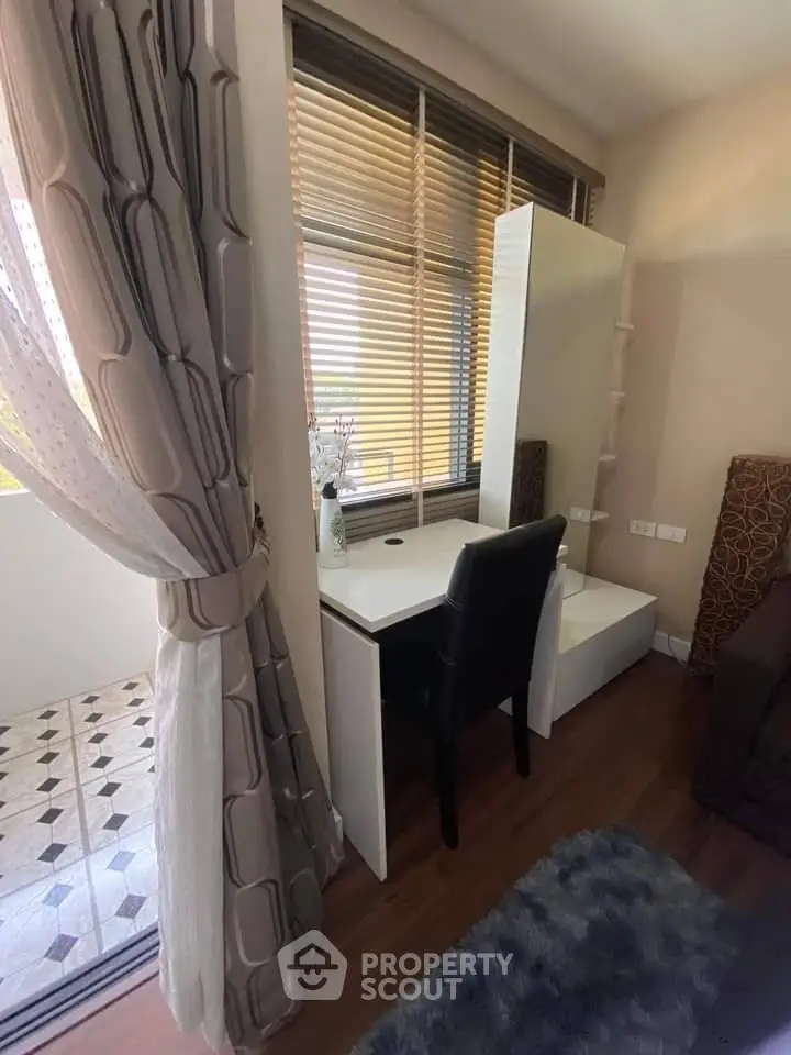 Cozy bedroom corner with desk and chair near window and balcony access.