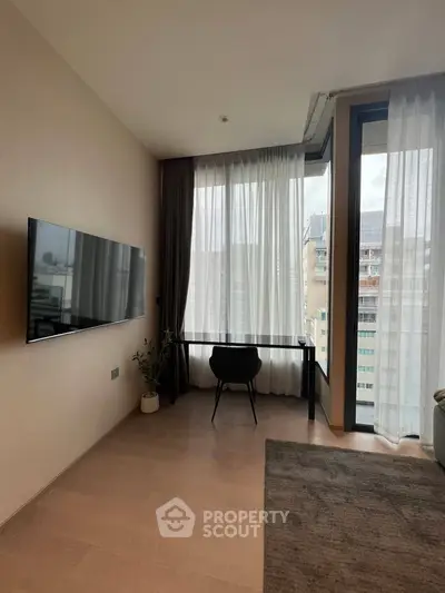 Modern living room with large windows and sleek TV setup in urban apartment.