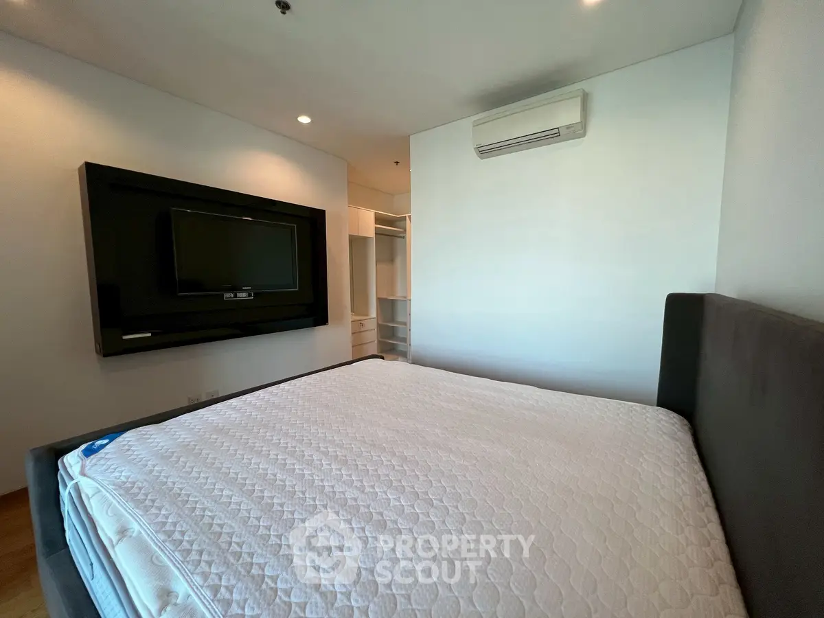 Spacious bedroom with modern TV setup and air conditioning, ideal for comfort and relaxation.