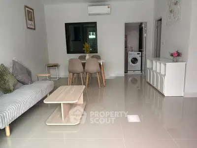 Modern living room with sleek furniture and washing machine in open layout apartment.