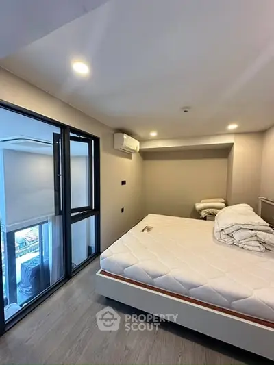 Modern bedroom with large windows and city view, featuring a comfortable bed and sleek design.