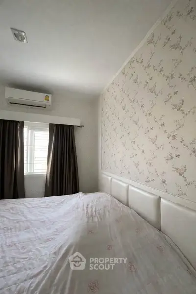 Cozy bedroom with floral wallpaper and air conditioning, perfect for relaxation.