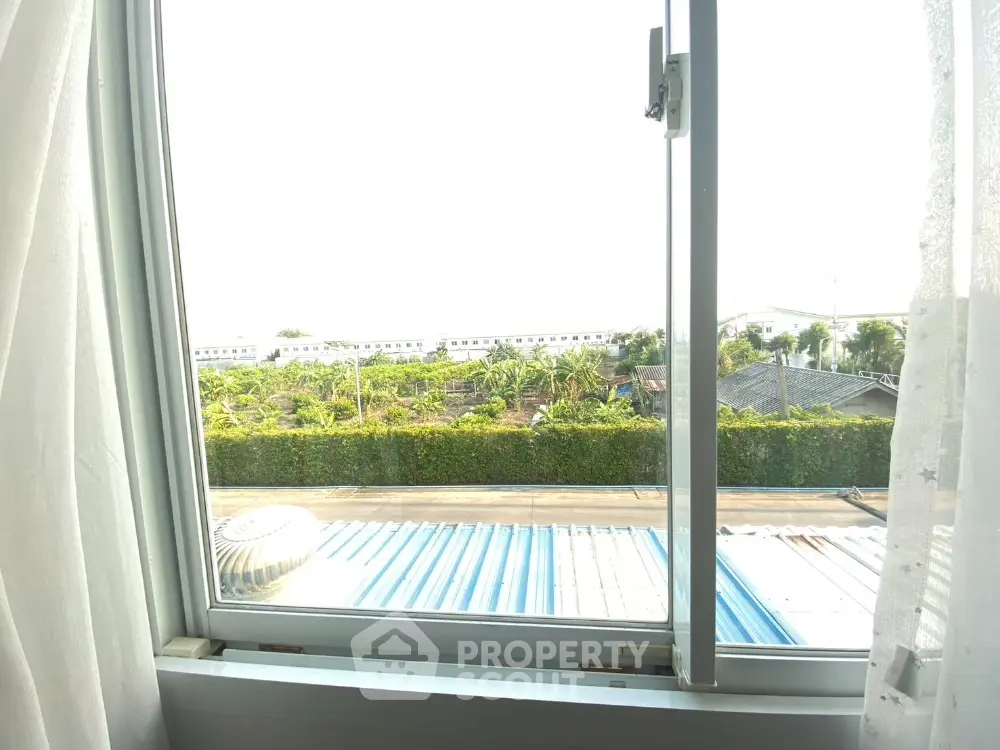 Bright and airy room with a view of lush greenery and a clear sky, seen through an open window, offering a serene living environment.