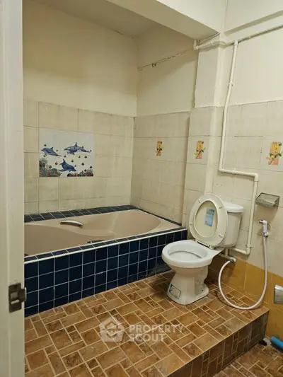 Cozy bathroom with tiled bathtub and toilet in a compact layout, ideal for small apartments.