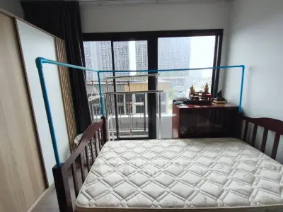Cozy bedroom with large window and city view, featuring a comfortable bed and ample natural light.