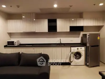 Modern kitchen with sleek cabinets, washing machine, and microwave in stylish apartment.