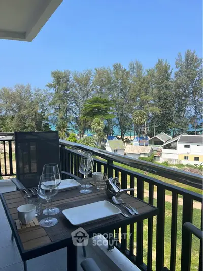 Stunning balcony view with outdoor dining set overlooking lush greenery and ocean horizon.