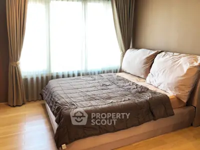 Cozy bedroom with large window and elegant curtains, featuring a comfortable bed and wooden flooring.