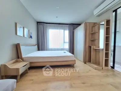 Spacious modern bedroom with wooden furniture and large window for natural light.