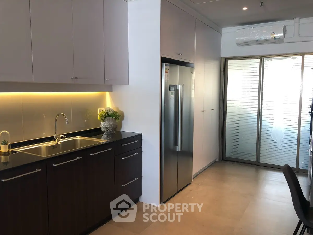 Modern kitchen with sleek cabinets and stainless steel fridge in a bright apartment.