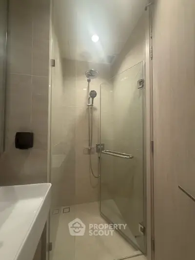 Modern bathroom with glass shower enclosure and sleek fixtures in a contemporary apartment.
