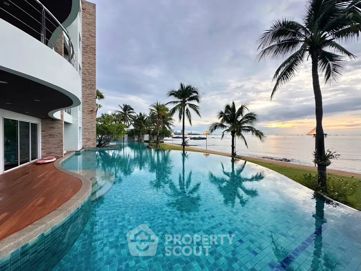Luxurious beachfront property with stunning infinity pool and palm trees at sunset.