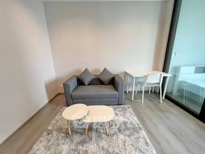 Modern living room with stylish gray sofa and chic coffee tables on a plush rug, adjacent to a cozy dining area.