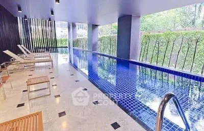 Luxurious indoor pool area with modern design and lush greenery view.