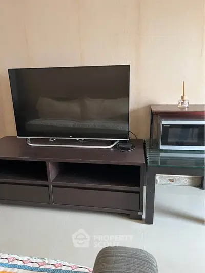 Modern living room with sleek TV and microwave on stylish furniture.