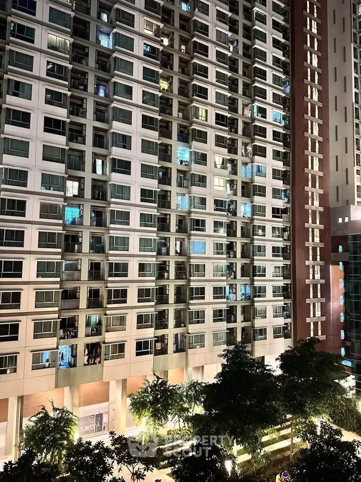 Stunning high-rise building exterior with illuminated windows and lush greenery.
