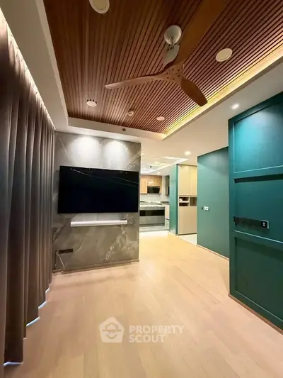 Modern living room with wooden ceiling, large TV, and open kitchen layout